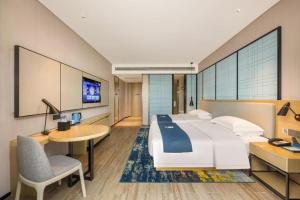 a hotel room with a large bed and a desk at Echarm Hotel Fangchenggang Qisha in Fangcheng