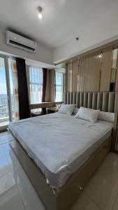 スラバヤにあるLuxury Family Apartments Anderson Benson at Supermall Pakuwonの窓のある部屋にある大きなベッドのある寝室