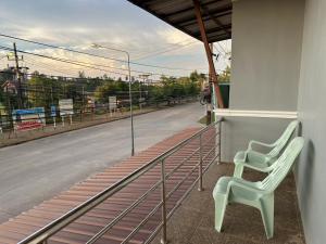 two white chairs sitting on a balcony with a street at Rest And Relax Hostel in Ban Mo Nae