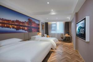 a hotel room with two beds and a painting on the wall at Vienna Hotel Jiangsu Dongtai Wanghai West Road in Dongtai +203 photos