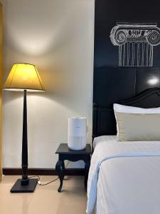 a bedroom with a bed and a lamp on a table at Nimman Mai Design Hotel Chiang Mai in Chiang Mai