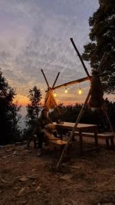 un uomo seduto su un tavolo da picnic di fronte al tramonto di Zelten Bir Luxury Forest Jungle Camps a Bīr Altre 8 foto