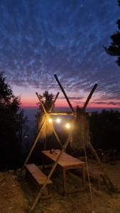 un tavolo da picnic con un mulino a vento e un tramonto sullo sfondo di Zelten Bir Eco Camp's & Cafe a Bīr