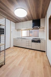 a kitchen with white cabinets and a wooden ceiling at 勝清居 大阪獨棟車庫民宿 千日前線新深江站2分一線直達 難波日本橋 全新裝修3LDk in Osaka