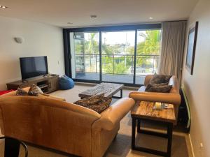 a living room with two couches and a tv at Beach Getaway in Mount Maunganui