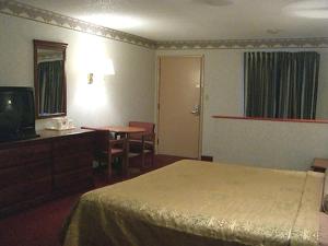 a hotel room with a bed and a desk and a television at Red Carpet Inn Williamstown in Williamstown
