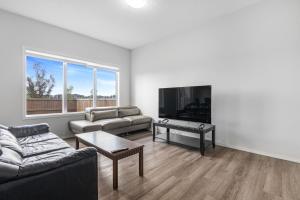 un salon avec un canapé et une télévision à écran plat dans l'établissement EasyStay - Close to Edmonton Airport, Shared Washroom, à Edmonton
