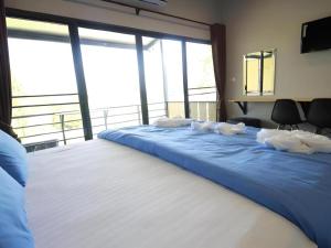 1 cama grande en una habitación con ventanas grandes en Maderbua hotel, en Udon Thani 10 fotos más