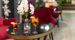 a table with two glasses and a vase of flowers at PLAZA INN Graz City in Graz +66 photos