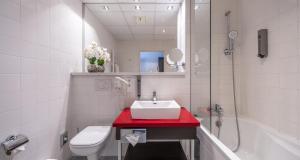 a bathroom with a sink and a toilet and a shower at PLAZA INN Graz City in Graz