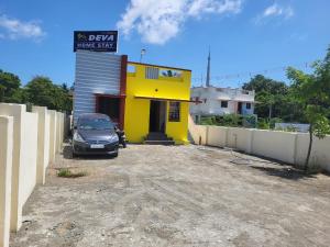 un coche aparcado delante de un edificio amarillo en Deva home stay, en Rameswaram