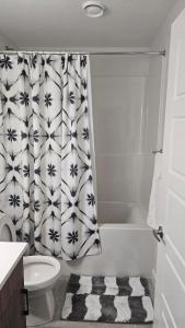 a bathroom with a toilet and a shower curtain at Welcome to Snug Spot - Cozy Studio in The Greens in Regina