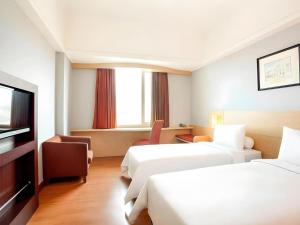 a hotel room with two beds and a flat screen tv at Hotel Horison Arcadia Heritage Surabaya in Surabaya