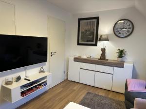 a living room with a tv and a clock on the wall at Lütt Lubotne in Laboe