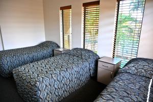 a hotel room with two beds and two windows at Western Gateway Motel and Apartments in Emerald