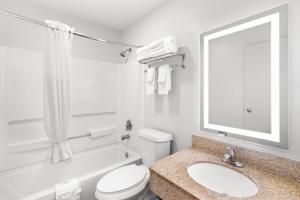 Un baño con inodoro, lavabo y espejo. en Quality Inn Atlanta Airport-Central, en Atlanta 31 fotos más