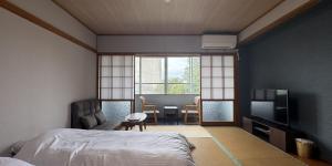 a bedroom with a bed and a table and a television at つるや旅館 in Yamanouchi