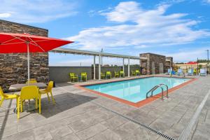 a swimming pool with a table and chairs and an umbrella at Home2 Suites By Hilton Marion in Marion