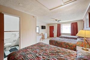 a hotel room with two beds and a bathroom at Capital O Hotel Beeville - US 181 in Beeville