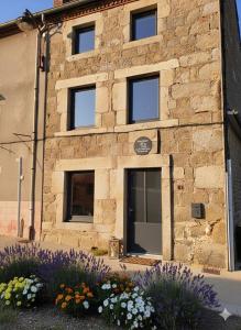 a stone building with flowers in front of it at Escapade bien-être avec Sauna et Balnéo - ChezBross' La Parenthèse in Aboën