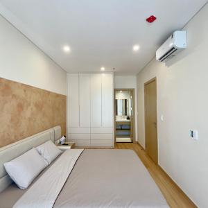 a bedroom with a large bed and a white wall at Pi & Pu Home- Free Gym & Pool- Sentosa Sky Park Hai Phong in An Khê