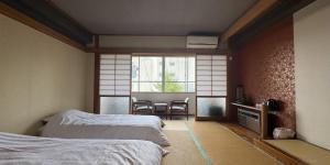 a room with two beds and a table and a window at つるや旅館 in Yamanouchi +20 photos