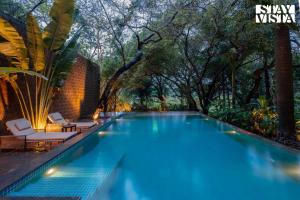 a swimming pool with trees in the background at StayVista at Moira by the River with Bonfire, BBQ in Moira