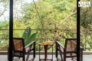 a table and chairs on a balcony with a tree at StayVista at Moira by the River with Bonfire, BBQ in Moira