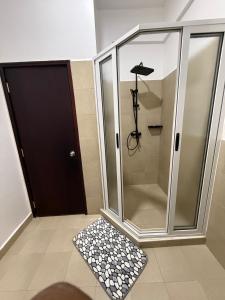 Una ducha de cristal con puerta negra y suelo de baldosas. en Cozy 1-Bedroom Apartment at Pearl Marina, Garuga, en Entebbe