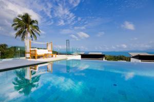 a swimming pool with a palm tree and the ocean at Code Samui Hotel in Mae Nam