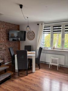 uma sala de jantar com mesa e cadeiras e um relógio em Gierymskiego Loft em Gliwice