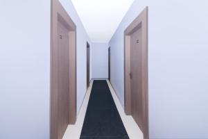 un couloir vide avec des portes en bois et un tapis noir dans l'établissement Super Collection O Ranchi Station Near Rajendra Chowk Formerly Bodhraj Paradise, à Rānchī