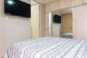 ein Schlafzimmer mit einem Bett und einem Fernseher an der Wand in der Unterkunft Flat Equipado Callao Cerca al Aeropueto Jorge Chávez 2 Dormitorios in Lima