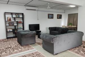 Sala de estar con 2 sofás de cuero y TV en DRH Villa, en Ipoh