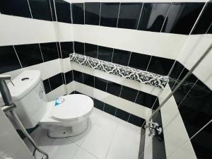 ein Badezimmer mit Toilette und schwarz-weißen Fliesen in der Unterkunft T&A Building in Manila