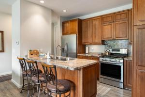 kuchnia z drewnianymi szafkami oraz wyspa z barowymi stołkami w obiekcie Riverside Retreat condo w mieście Winter Park