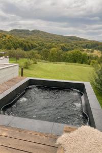 a hot tub on a deck with a view of a golf course at Le Chalet M - Cabană cu o panoramă de poveste. in Şurdeşti