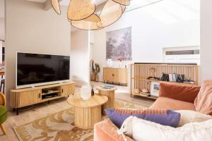 a living room with a couch and a flat screen tv at Magnifique Appartement Biscarrosse Bourg in Biscarrosse