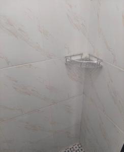 a bathroom with white marble walls and a shelf on the wall at Penginapan JANNAH Syariah in Takengon