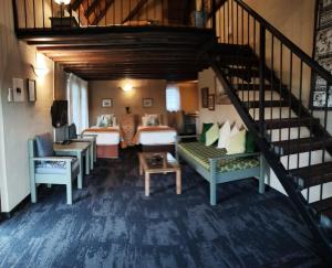 a living room with a staircase with chairs and tables at Ascot Bush Lodge & Spa in Pietermaritzburg