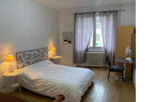 a bedroom with a bed and two tables and a desk at Hôtel Brasserie Le Lion d'Or in Meximieux