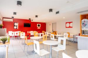 a restaurant with tables and chairs and a red wall at Premiere Classe Bordeaux Nord - Lac in Bordeaux