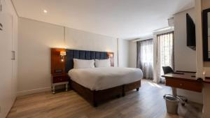 ein Hotelzimmer mit einem großen Bett und einem Schreibtisch in der Unterkunft ANEW Hotel Hatfield Pretoria in Pretoria