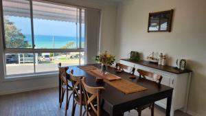 a dining room with a table and chairs and a large window at Bonny View Paradise in Bonny Hills