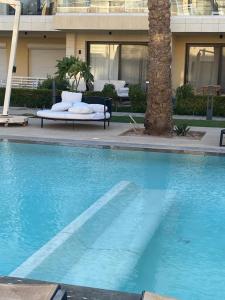 Una piscina azul con una palmera delante de un edificio. en Chic G Cribs Studio, en El Gouna 6 fotos más