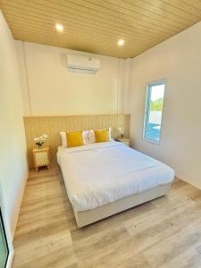 a bedroom with a bed with white sheets and yellow pillows at Montara villa Chaloklum Koh phangan in Chaloklum