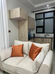 a white couch with two orange pillows in a kitchen at Cozy Homes in Ruaka