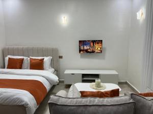 a bedroom with two beds and a couch and a tv at Serenity Residences Studio Ruaka Near Two Rivers & UN Gigiri in Ruaka