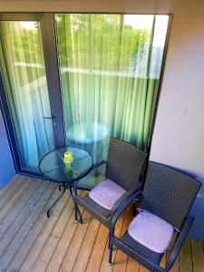 een balkon met een glazen tafel en twee stoelen bij Apartamentai Gintaras in Palanga