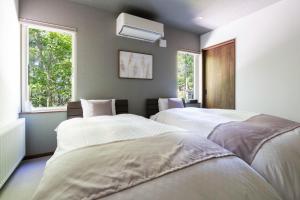 two beds in a room with two windows at 翠葉 Rusutsu in Rusutsu